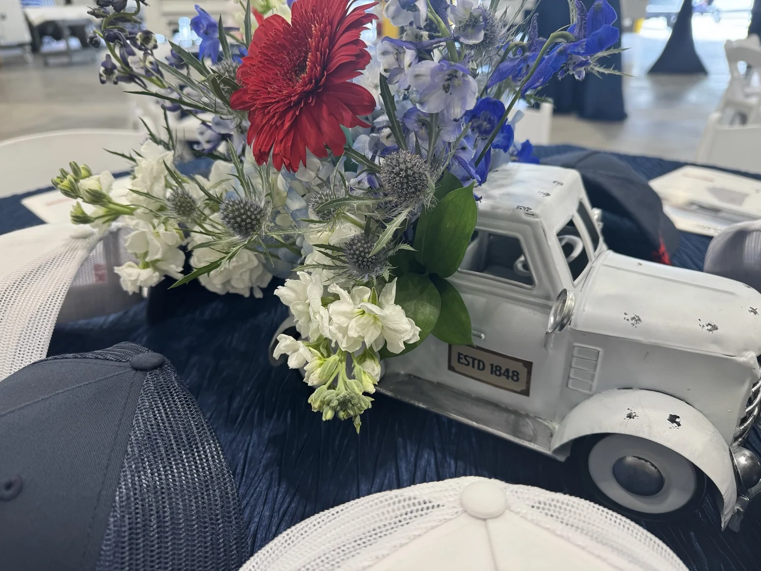 Close detail of a red, white and blue floral arrangement displayed in a vintage truck centerpiece on a navy event table.